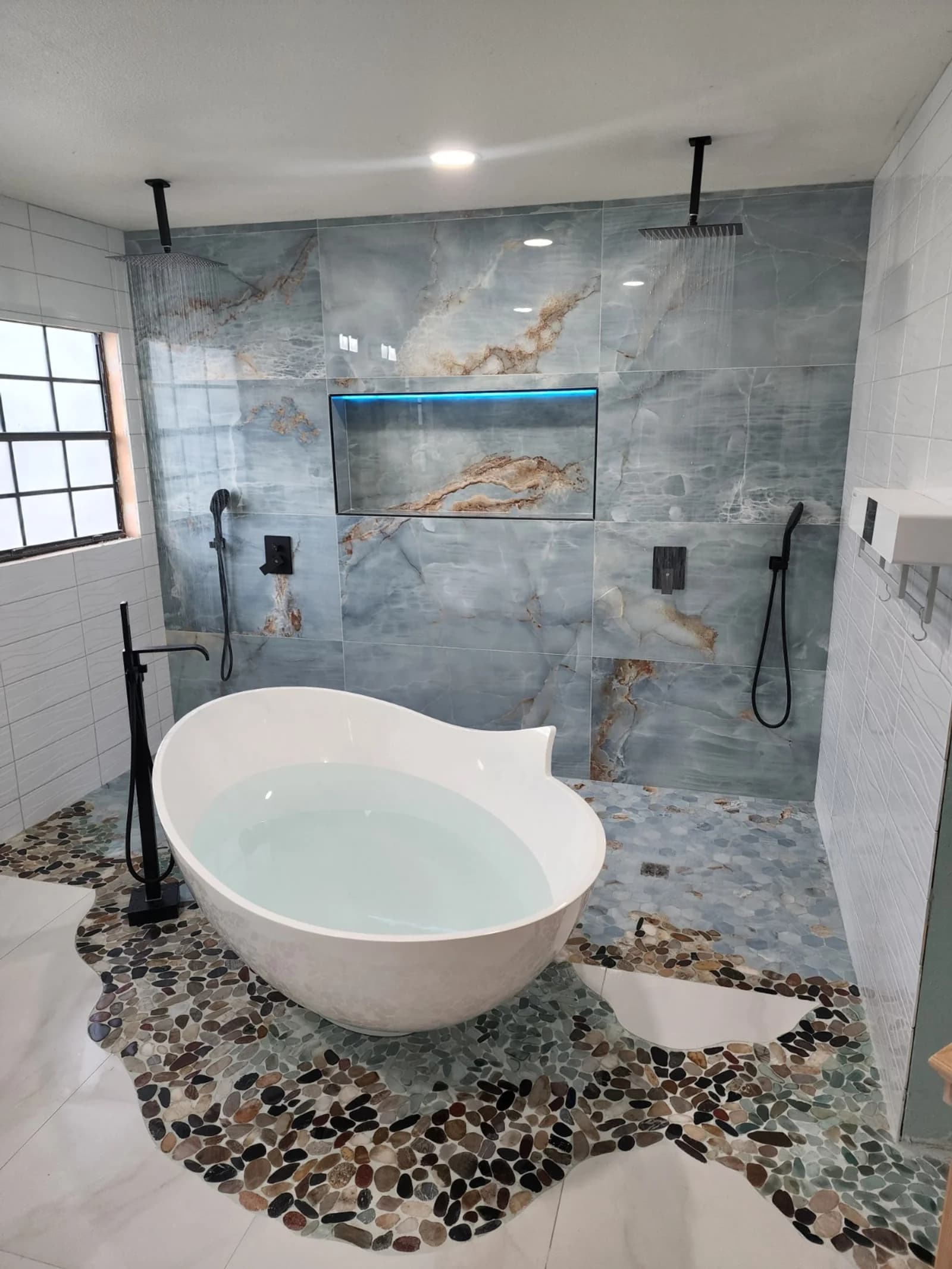 Master bathroom with freestanding tub and blue onyx wall