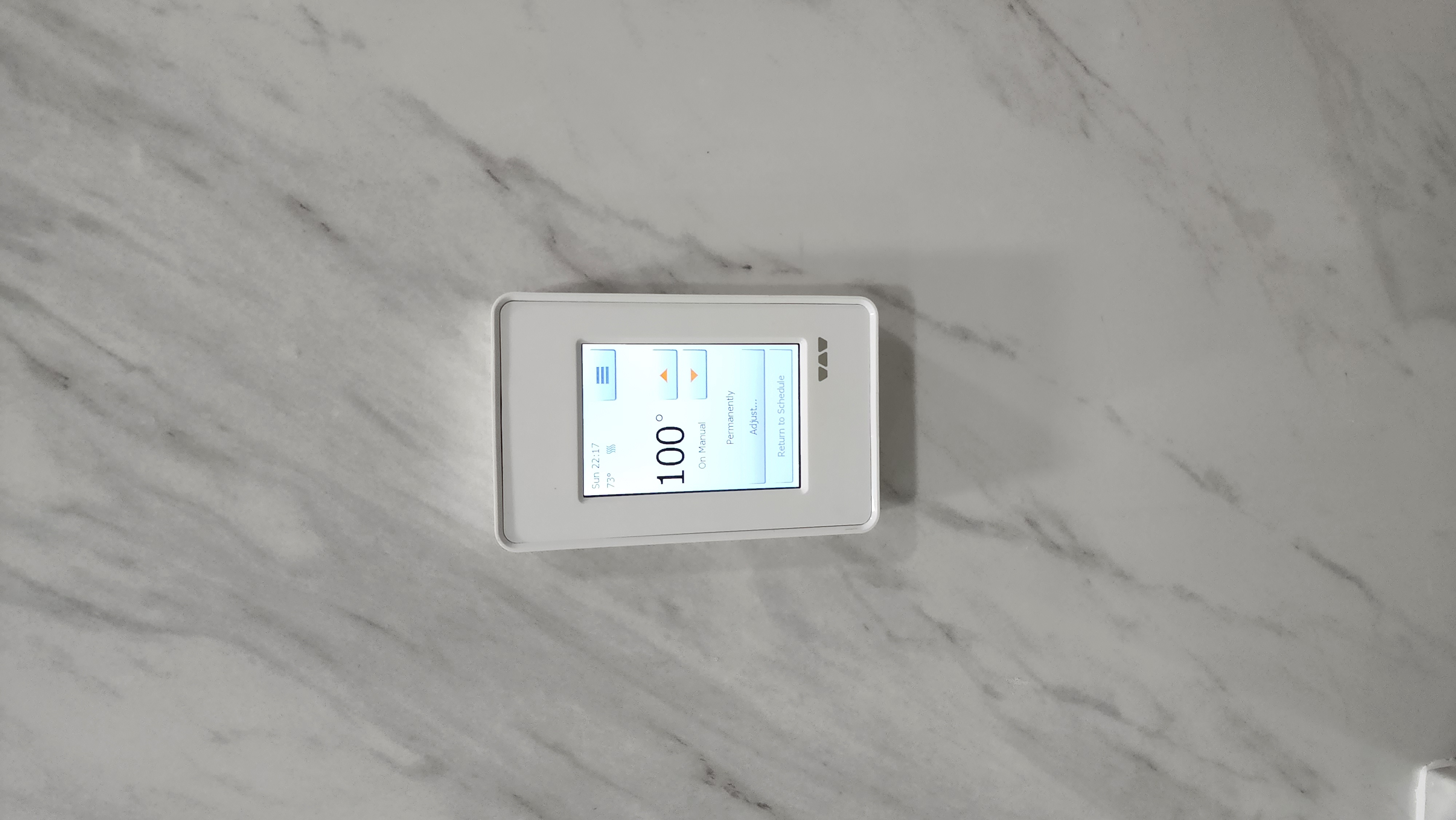 Schluter DITRA-HEAT touchscreen thermostat installed on a marble tile wall showing the floor temperature