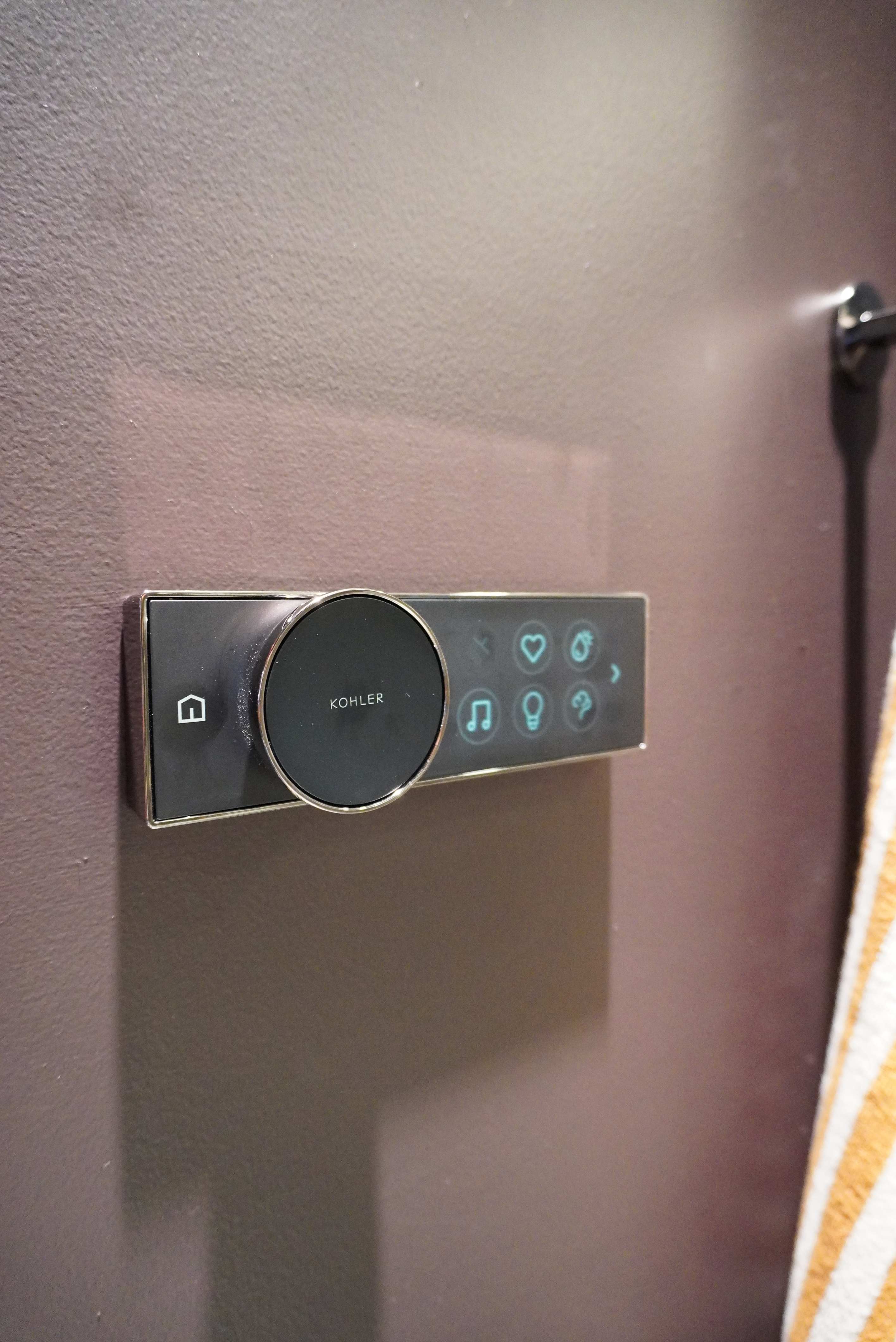 Kohler DTV+ controller with a chrome-ringed dial and backlit touch icons for presets, lighting, steam, and audio