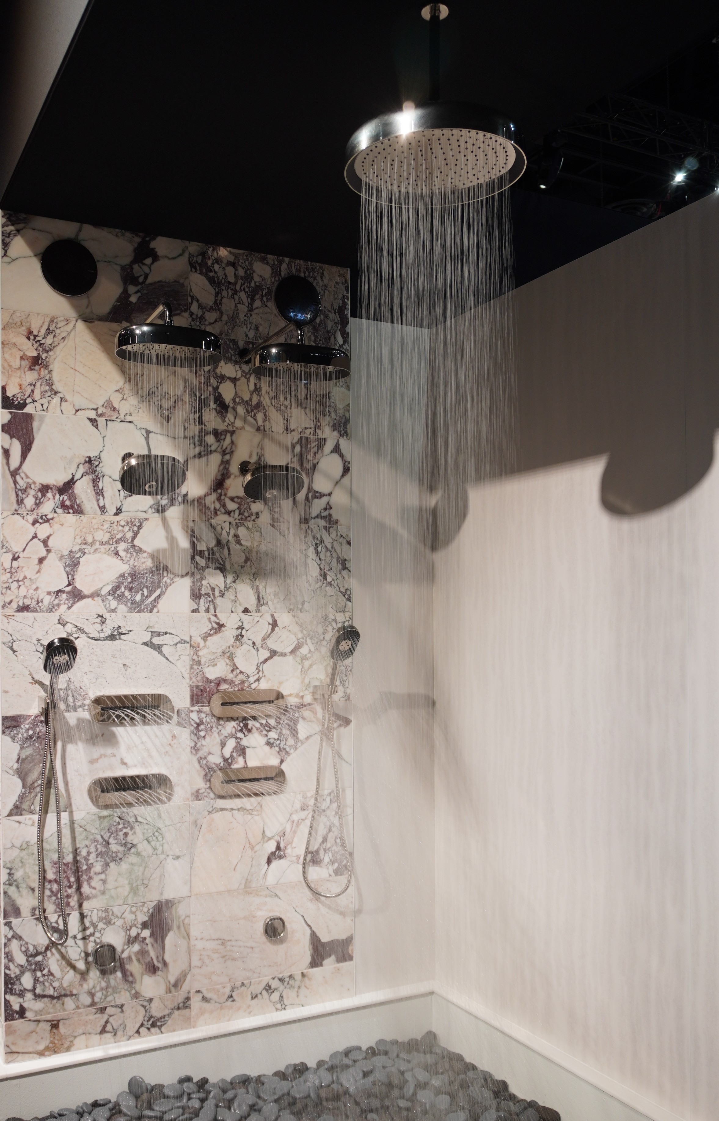 Luxury marble shower with polished chrome rain heads, body-spray jets, and a handshower all running at once